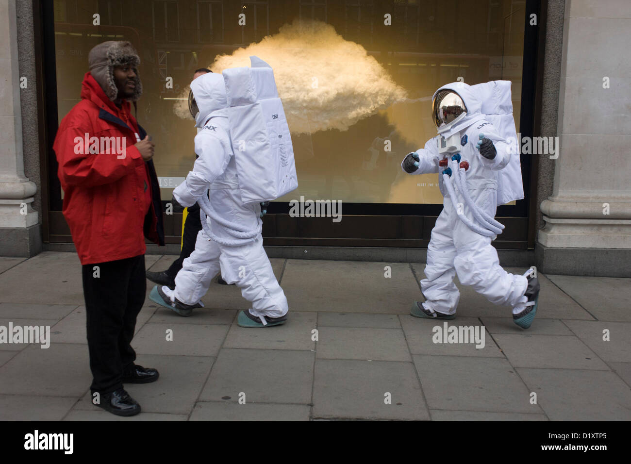 Londres, Royaume-Uni. 8 Janvier 2013 : deux personnages habillés comme des astronautes de la NASA lune marcher, marcher le long d'Oxford Street à l'extérieur de la grand magasin Selfridges à Londres. Sortant de la porte de cette fameuse boutique, les deux astronautes portent les fameux sacs jaunes comme d'autres entrent et sortent de la grande porte. Selfridges, également connu sous le nom de Selfridges & Co, est une chaîne de grands magasins haut de gamme au Royaume-Uni. Elle a été fondée par Harry Gordon Selfridge. Credit : RichardBakerNews / Alamy Live News Banque D'Images