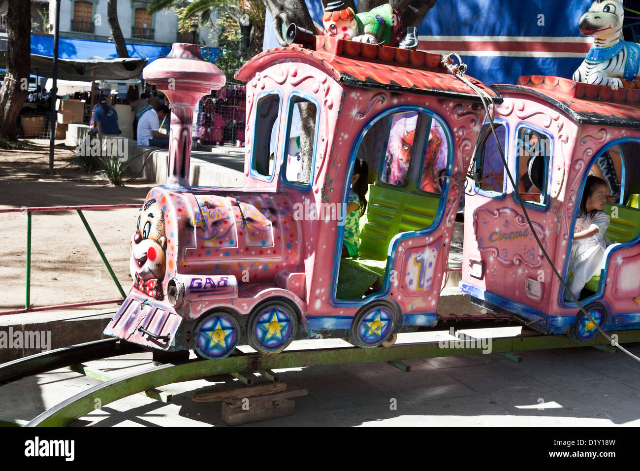 Les enfants peuvent s'étourdissait dans ride légèrement coloré bleu rose délabré & lime petit train à Llano park Saturday market Oaxaca Mexique Banque D'Images