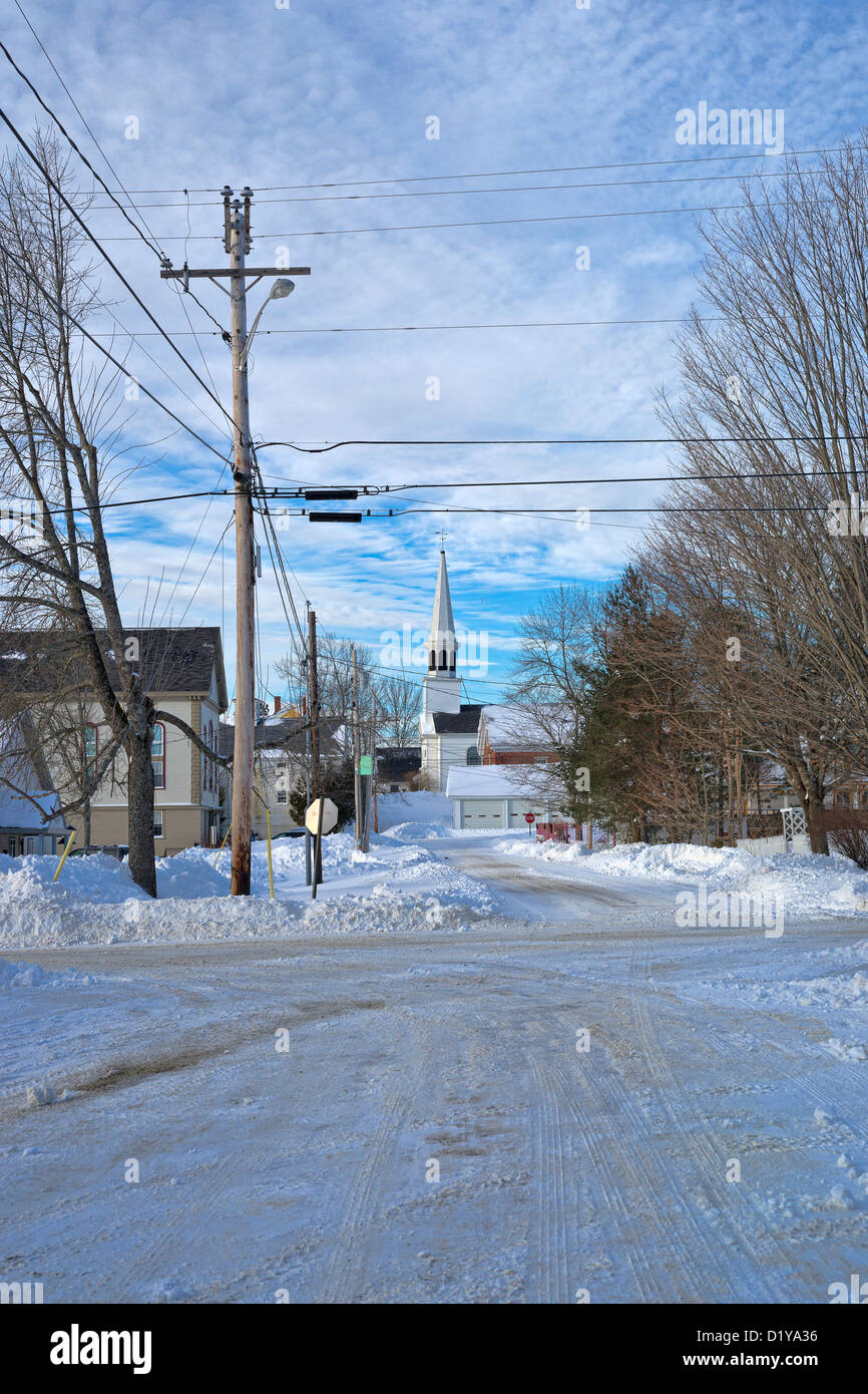 La Nouvelle Angleterre rurale scène rurale avec des routes couvertes de neige, de téléphone et les fils électriques, les arbres et une église lointaine. Banque D'Images