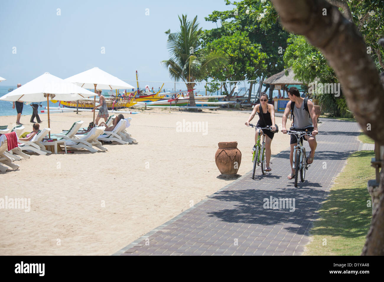 Jeune couple riding bikes sur le front de mer à l'hôtel Hyatt Regency de Sanur, Bali, Indonésie Banque D'Images