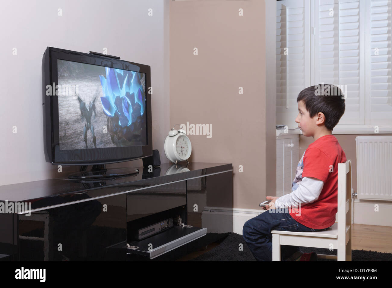 Jeune garçon regarde la télévision toute seule à la maison Photo Stock Alamy