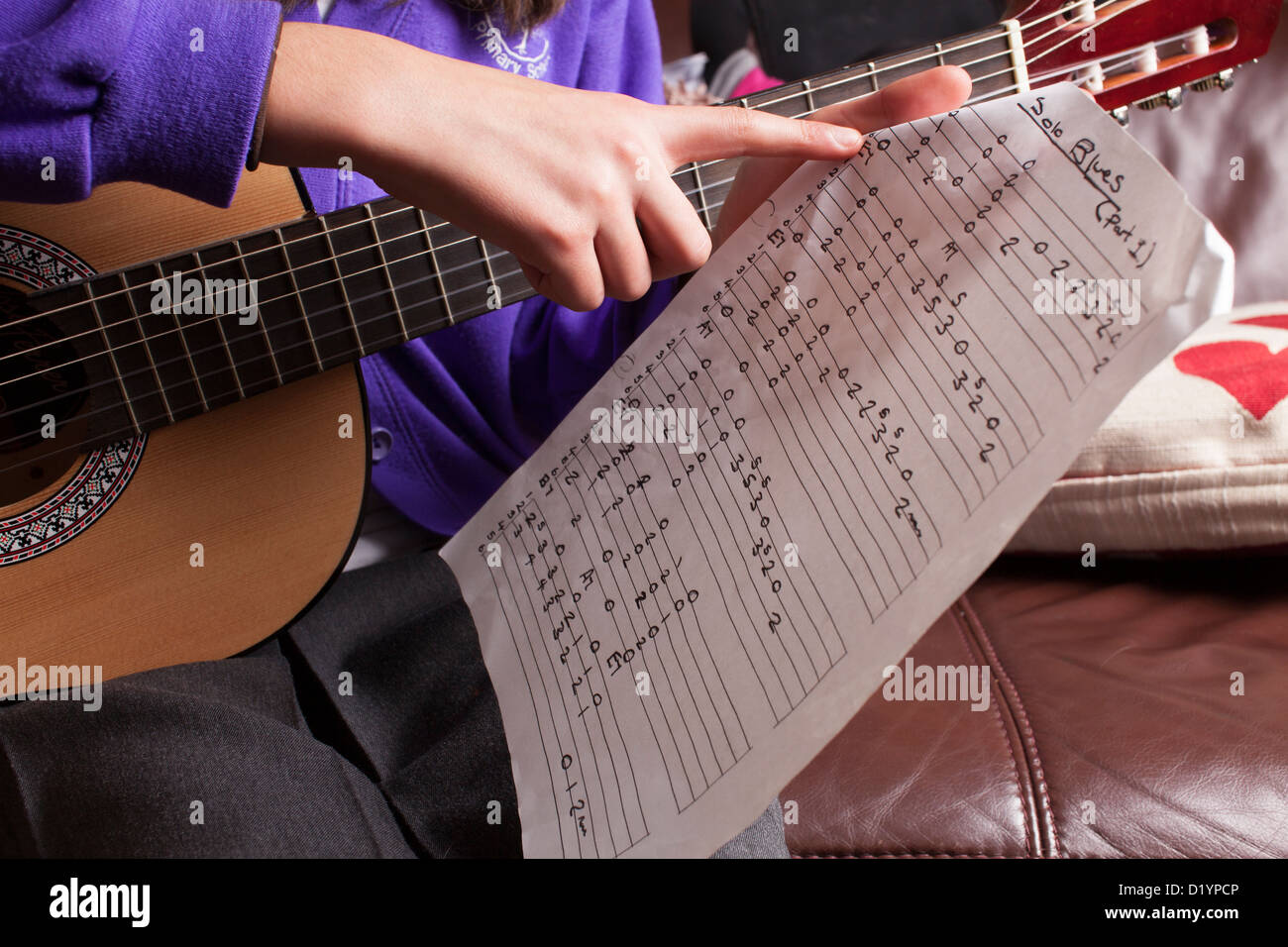 Lecture d'écolière des accords sur sa guitare. Banque D'Images