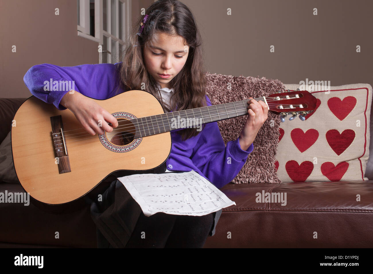 Lycéenne pratiquant des accords sur sa guitare. Banque D'Images