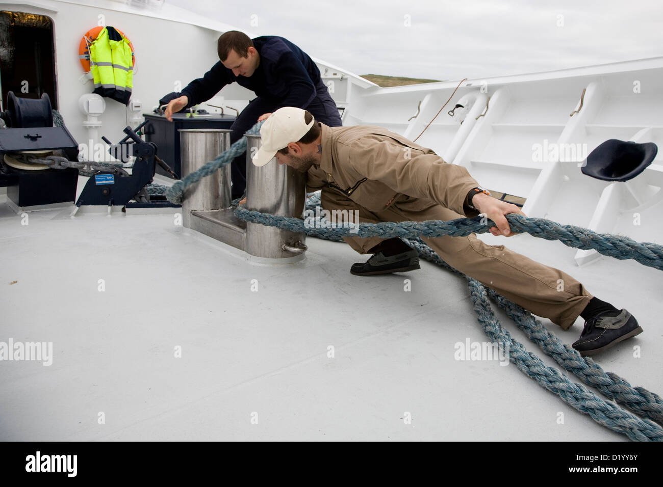 Deux hommes à bord de l'yacht Hanse Explorer tirant une corde d'amarrage, voyage autour des îles Shetland, Ecosse, Grande-Bretagne Banque D'Images
