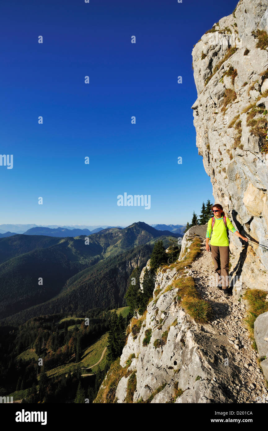 Femme marche sur un sentier au rocher, un Brunnstein, Préalpes bavaroises, Upper Bavaria, Bavaria, Germany Banque D'Images