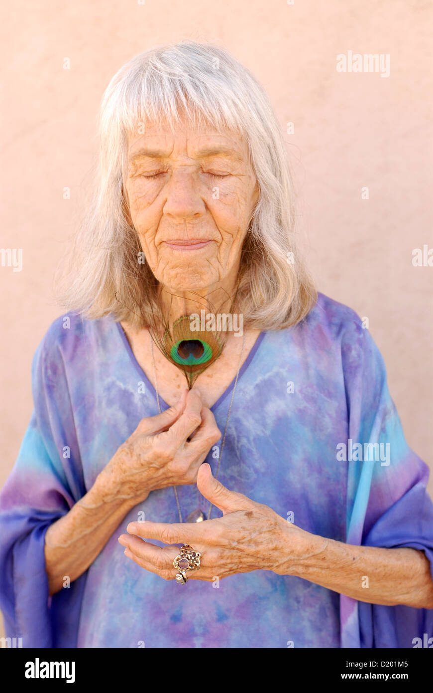 Nouvel âge belle grand-mère avec une plume de paon pressé contre sa gorge. Banque D'Images