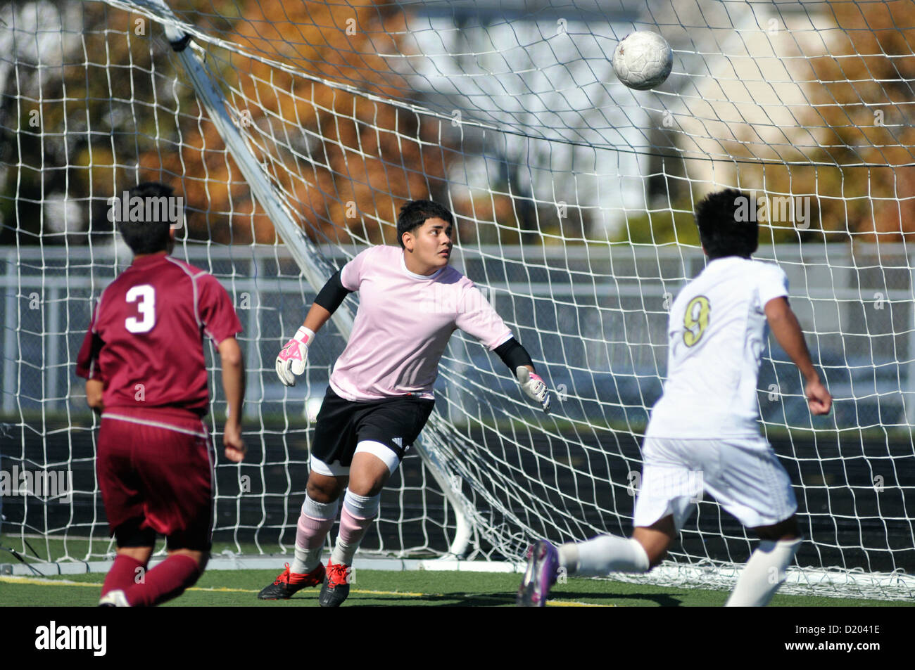 Gardien de but de soccer observe un shot pour le coin du net et un but pendant un match de l'école secondaire. USA. Banque D'Images