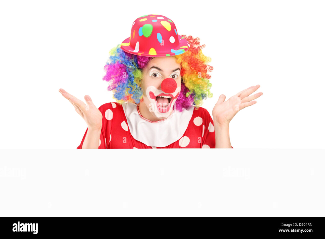 Clown mâle gesticulant derrière panneau vide isolé sur fond blanc Banque D'Images