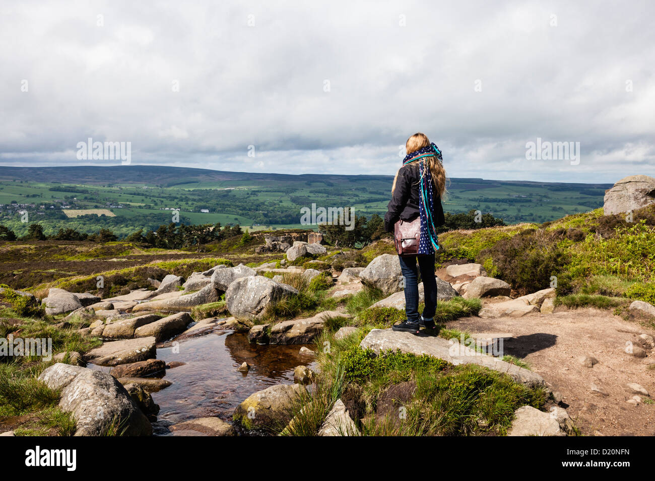 Une femme se tient et contemple l'ofver voir la Vache et son veau Rocks, en haut d'Ilkley Moor, West Yorkshire, Royaume-Uni Banque D'Images
