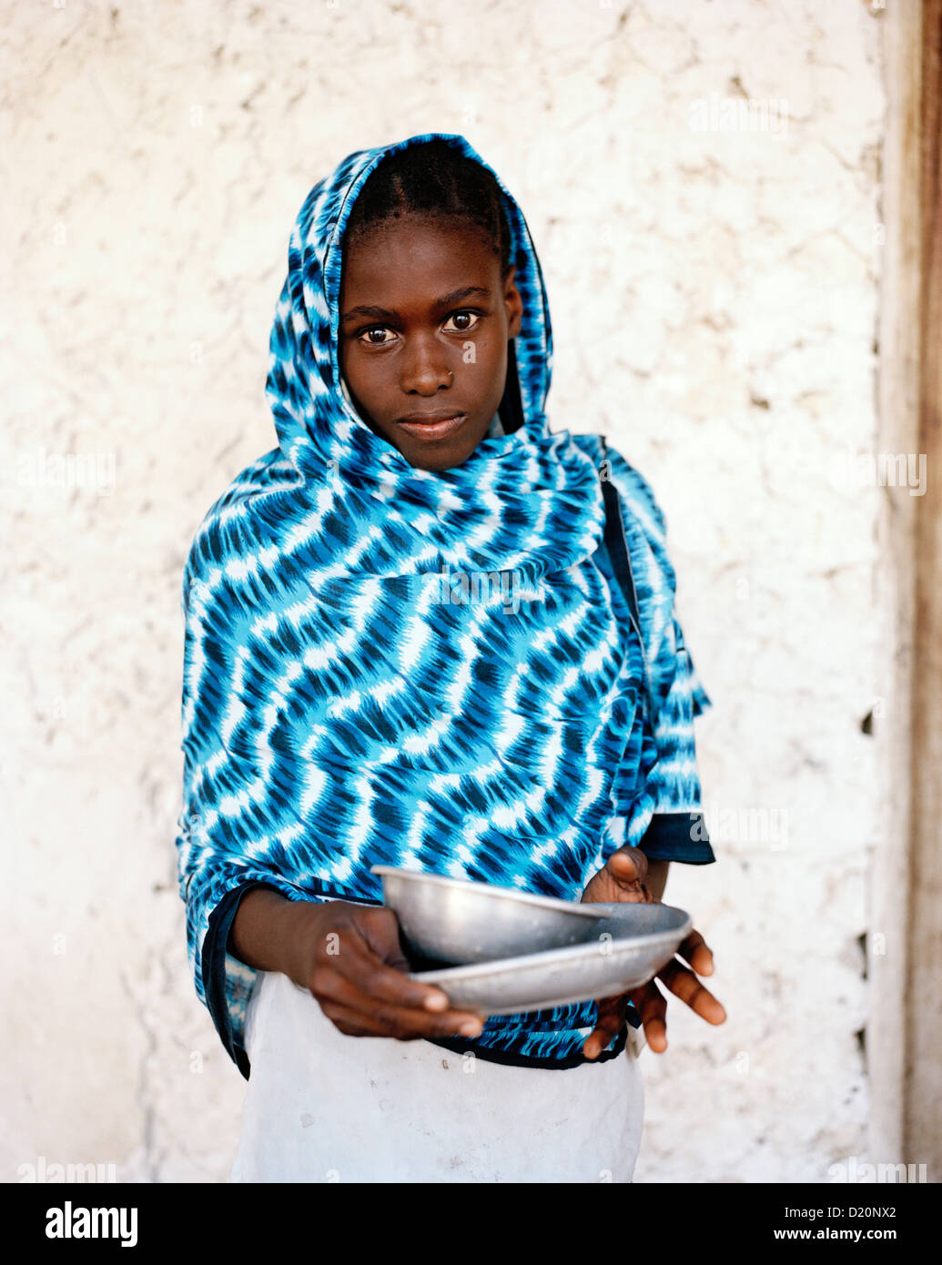 Fille avec tissu Kanga bleu en face de maison en pierre de corail, Jambiani village, Zanzibar, Tanzanie, Afrique de l'Est Banque D'Images