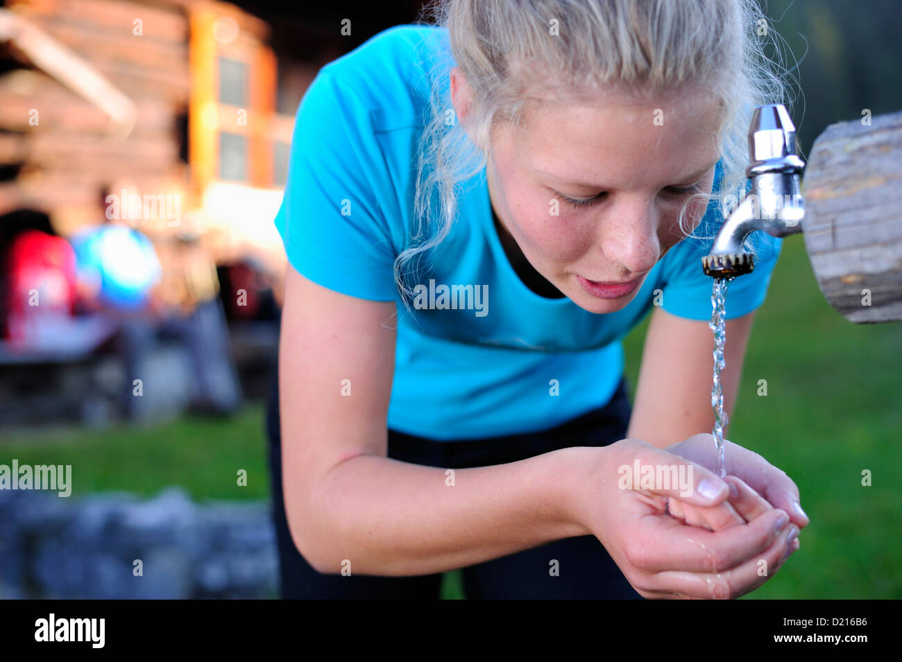 Jeune femme à boire de l'eau d'une fontaine, Unnutz, Alpes de Zillertal, Tyrol, Autriche Banque D'Images