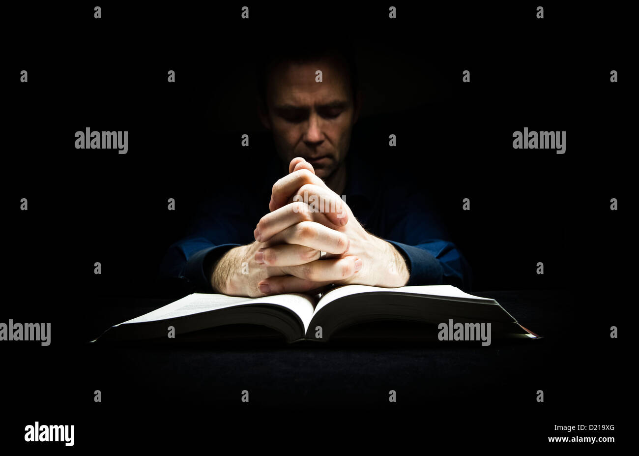 L'homme à prier Dieu avec ses mains reposant sur la bible. Banque D'Images