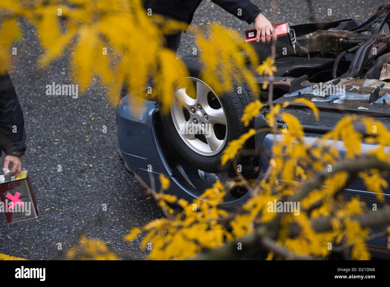 Deux hommes verser sur un véhicule renversé accelerant Banque D'Images