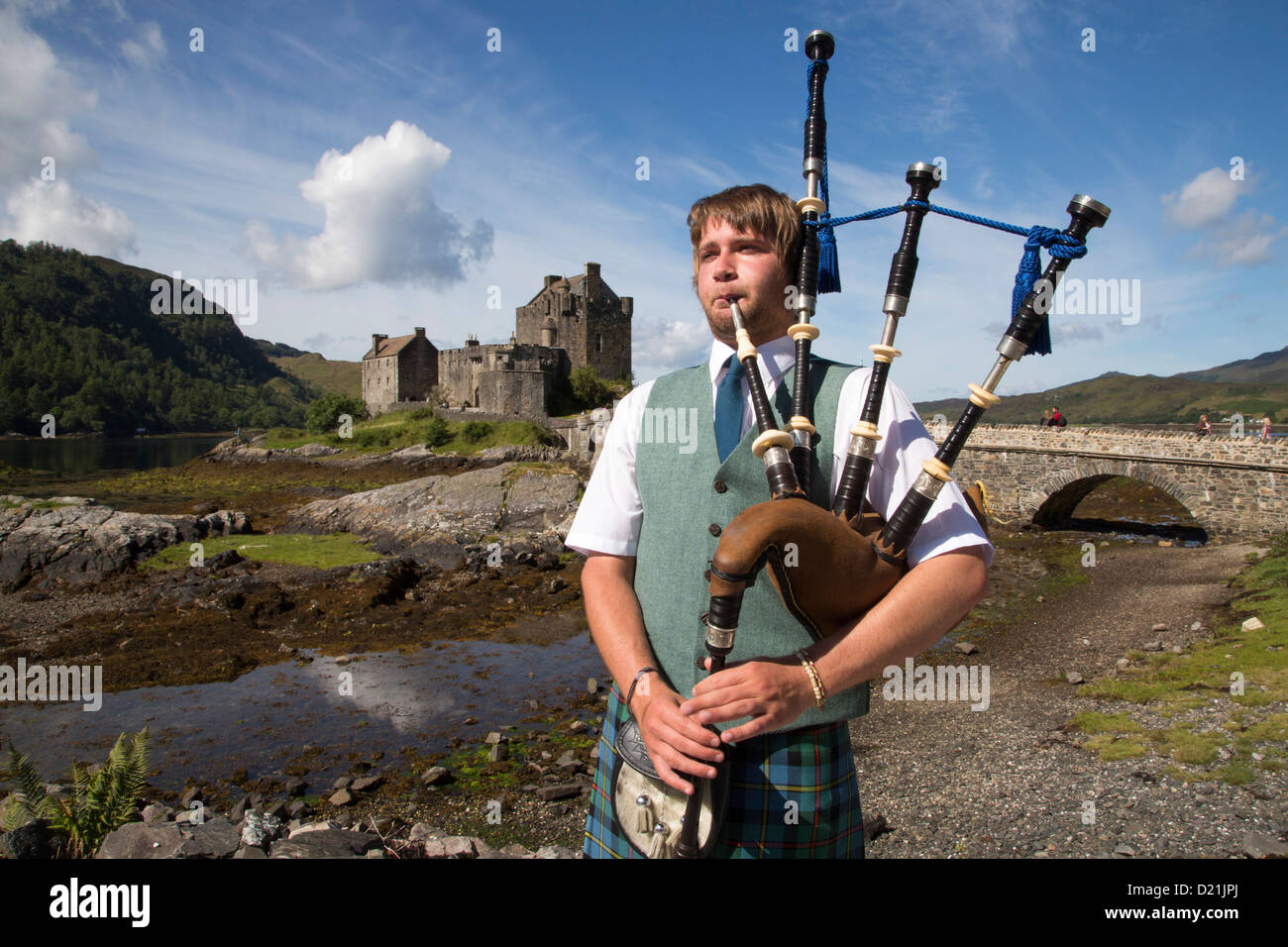 Jeune joueur de cornemuse devant le Château d'Eilean Donan à Loch Duich, près de Dornie, Highland, Ecosse, Royaume-Uni Banque D'Images