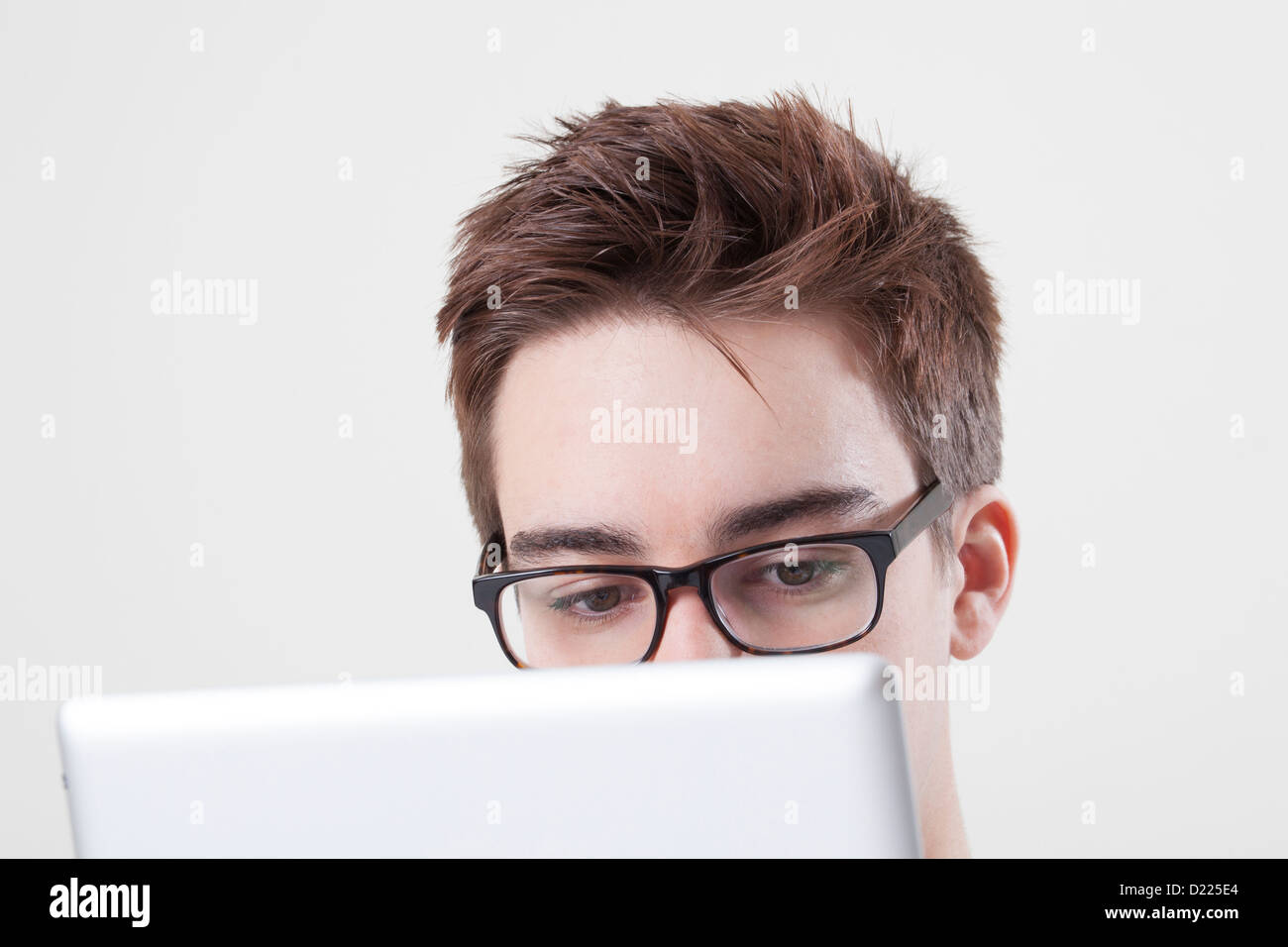 Jeune homme portant des lunettes à la recherche à l'écran de son ordinateur portable ou tablette numérique. Close up sur les yeux. Banque D'Images