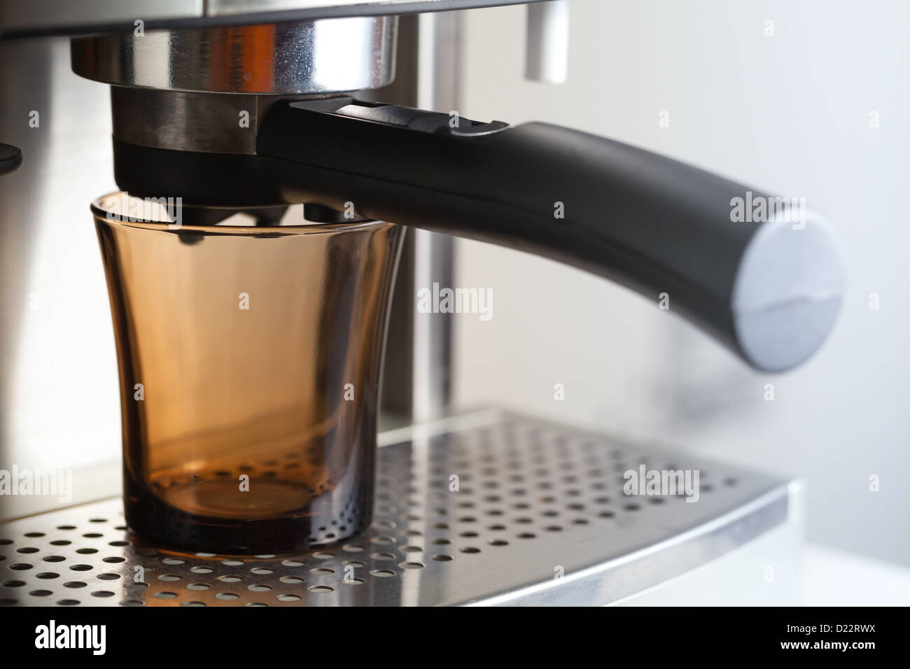 Tasse en verre foncé vide dans une machine à café expresso Banque D'Images