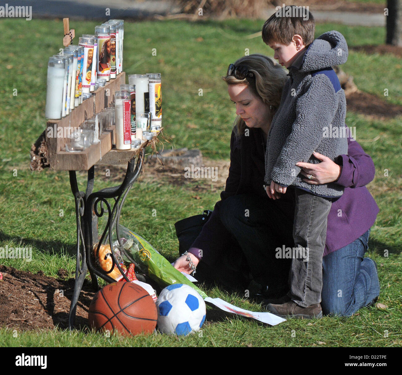 Newtown, Connecticut, USA-- Amy Collins et son fils, Andrew, 5, placé les dessins et allumé des bougies à l'extérieur de l'église St Rose de Lima à Newtown. Ils sont de Newtown. De nombreux résidents de la région ont visité l'église en tant que la communauté essaie de s'attaquer à la fusillade massacre de l'école élémentaire de Sandy Hook hier. Le tireur, Adam Lanza a tué 20 2 e année et six adultes à l'école élémentaire de Sandy Hook à Newtown dans une fusillade. Banque D'Images