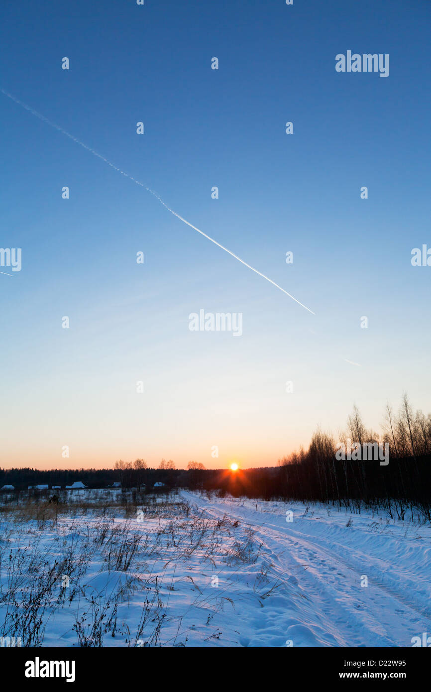 Ciel bleu et rose foncé sur le coucher du soleil et de la neige country road Banque D'Images