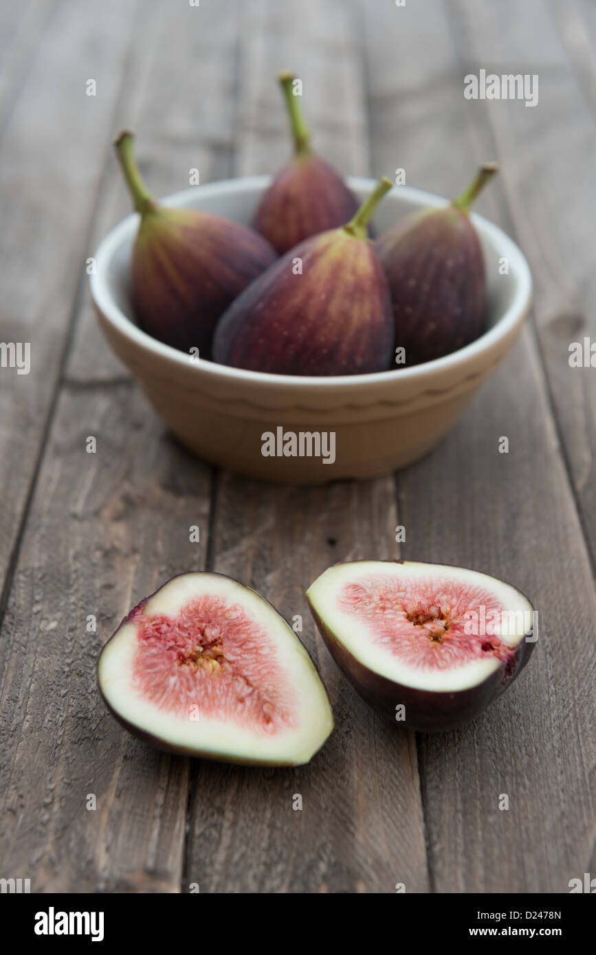 Figues dans un bol sur un fond de bois. Banque D'Images