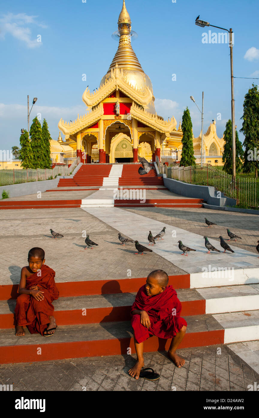 Deux jeunes moines bouddhistes novice assis sur mesures en dehors Maha Wizaya à Yangon Banque D'Images