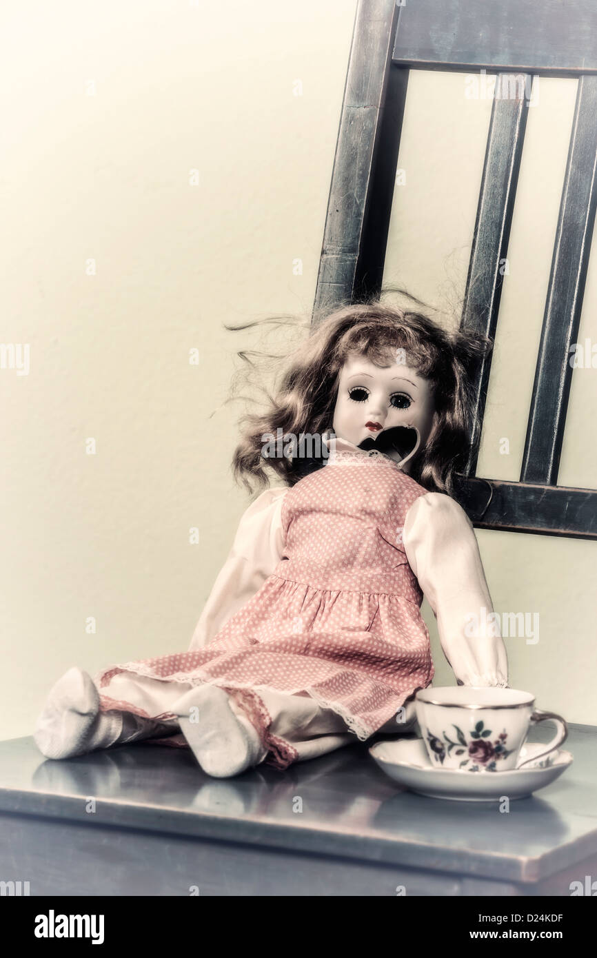Une vieille poupée cassée avec une tasse de thé Banque D'Images