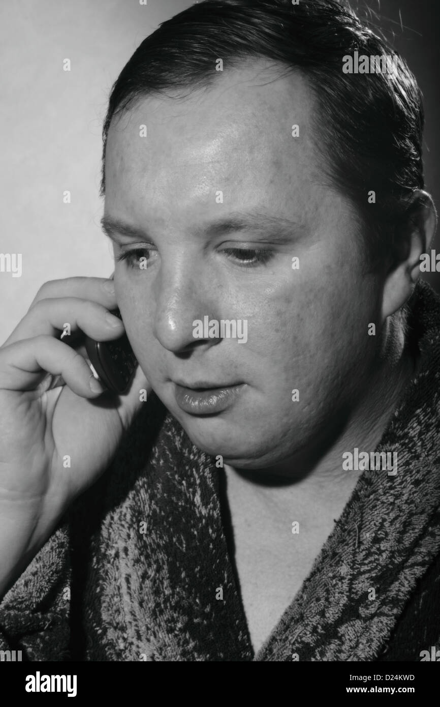 Jeune homme dans un peignoir talking on a cell phone Banque D'Images