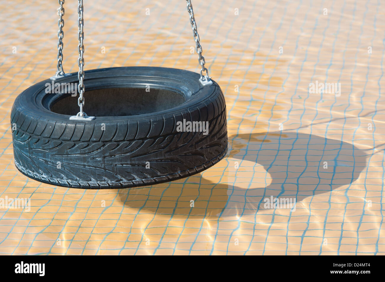 Image abstraite de balançoire pneu avec ombre dans l'eau peu profonde d'une piscine pour enfants Banque D'Images