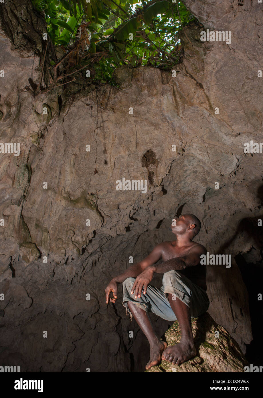 L'homme regardant un trou dans Momuni Grotte Sacrée. Bougainville, en Papouasie-Nouvelle-Guinée Banque D'Images