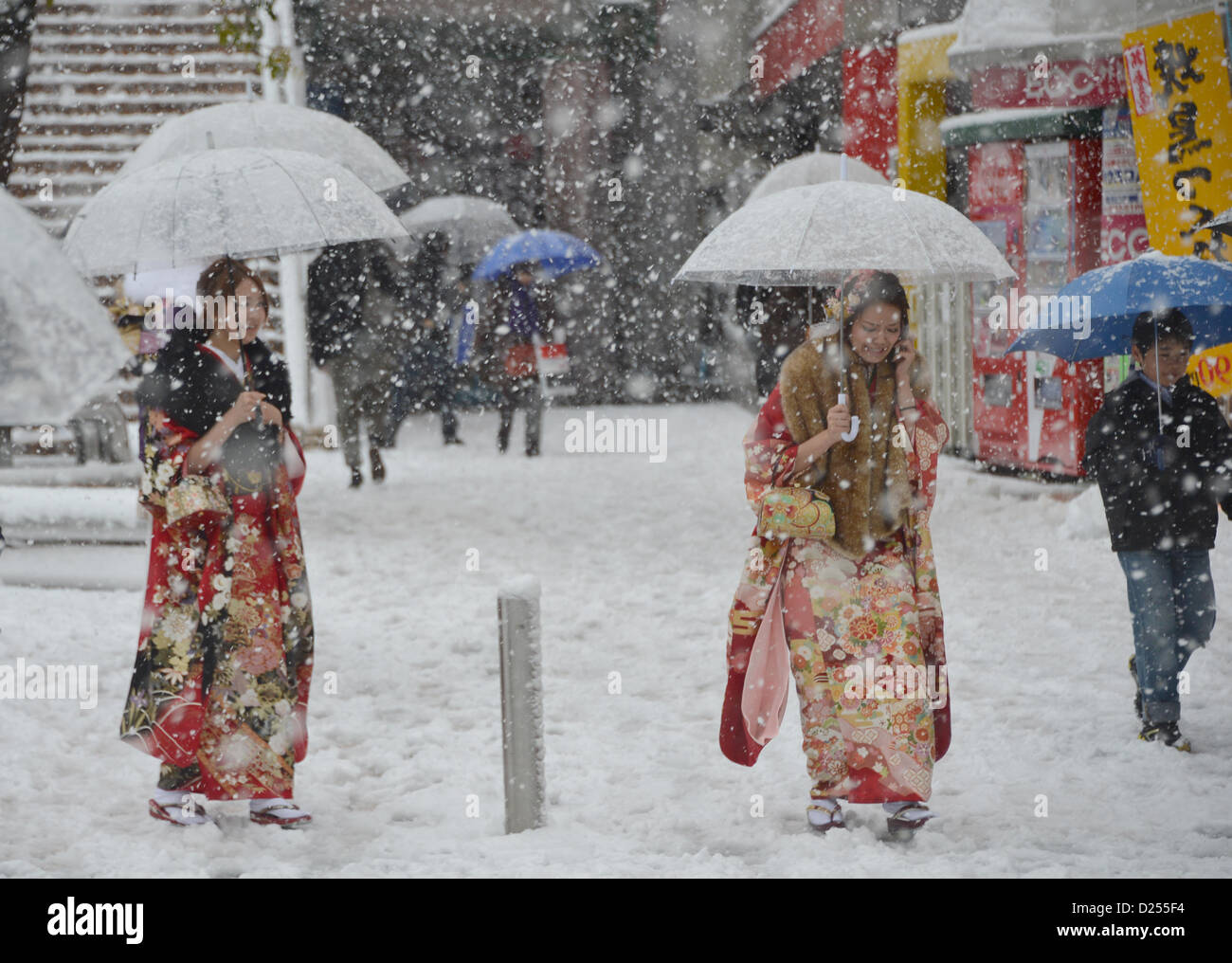 Tokorozawa, au Japon. 14 janvier 2013. Vêtus de robes de cérémonie, manches longues femmes japonaises hâte leur façon d'assister à un passage à l'âge d'une cérémonie à Tokorozawa, banlieue ouest de Tokyo, dans la neige qui tombe le lundi, Janvier 14, 2013. Sur 1 220 000 personnes en 20 ans ont célébré leur passage à l'âge dans tout le Japon. Une tempête d'hiver freak pouces de neige, couvrant la zone métropolitaine de Tokyo et ses environs avec des couvertures de première neige de la saison. (Photo de Natsuki Sakai/AFLO) AYF -mis- Banque D'Images