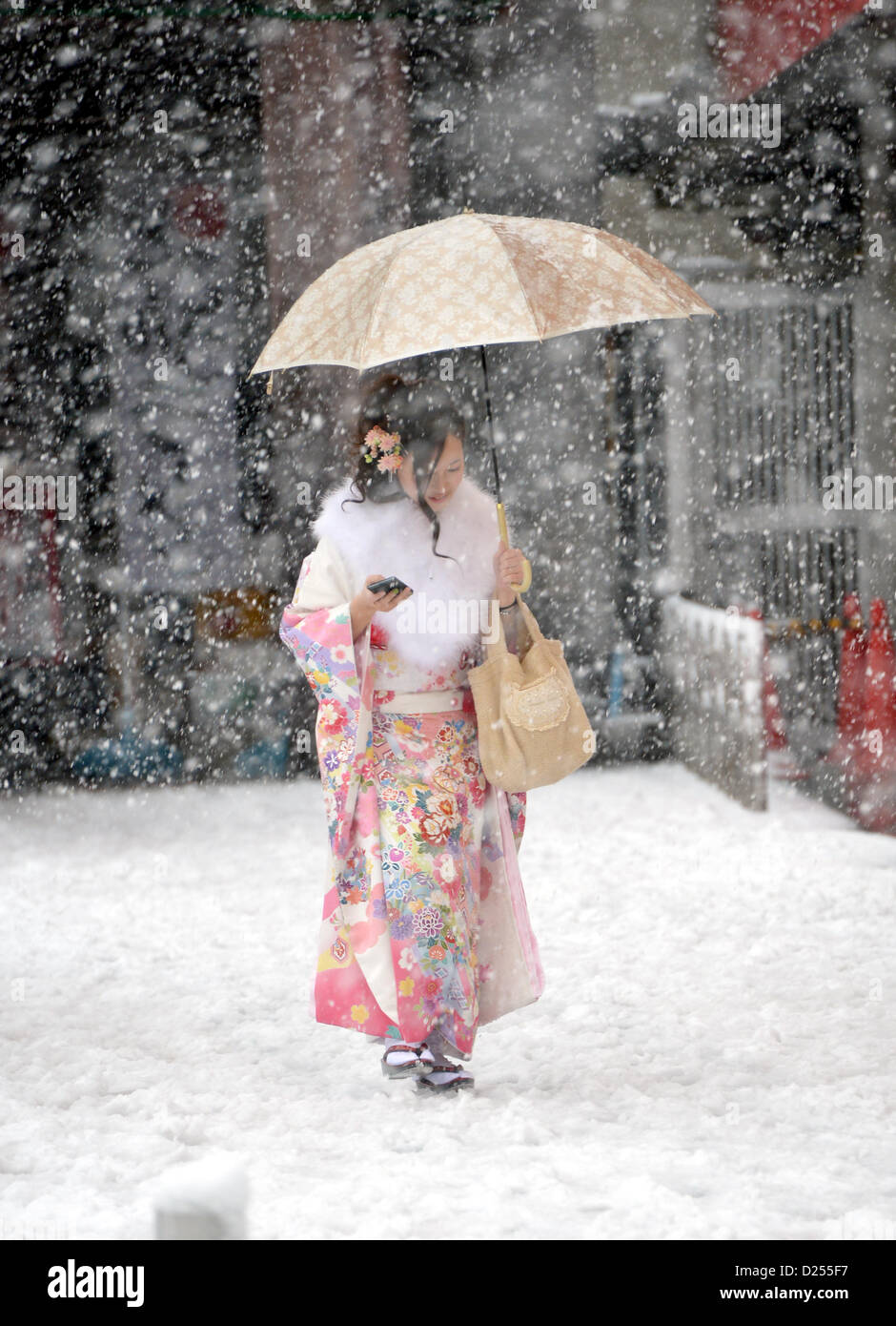 Tokorozawa, au Japon. 14 janvier 2013. Habillée d'une robe à manches longues de cérémonie, une japonaise se précipite sa façon d'assister à un passage à l'âge d'une cérémonie à Tokorozawa, banlieue ouest de Tokyo, dans la neige qui tombe le lundi, Janvier 14, 2013. Sur 1 220 000 personnes en 20 ans ont célébré leur passage à l'âge dans tout le Japon. Une tempête d'hiver freak pouces de neige, couvrant la zone métropolitaine de Tokyo et ses environs avec des couvertures de première neige de la saison. (Photo de Natsuki Sakai/AFLO) AYF -mis- Banque D'Images