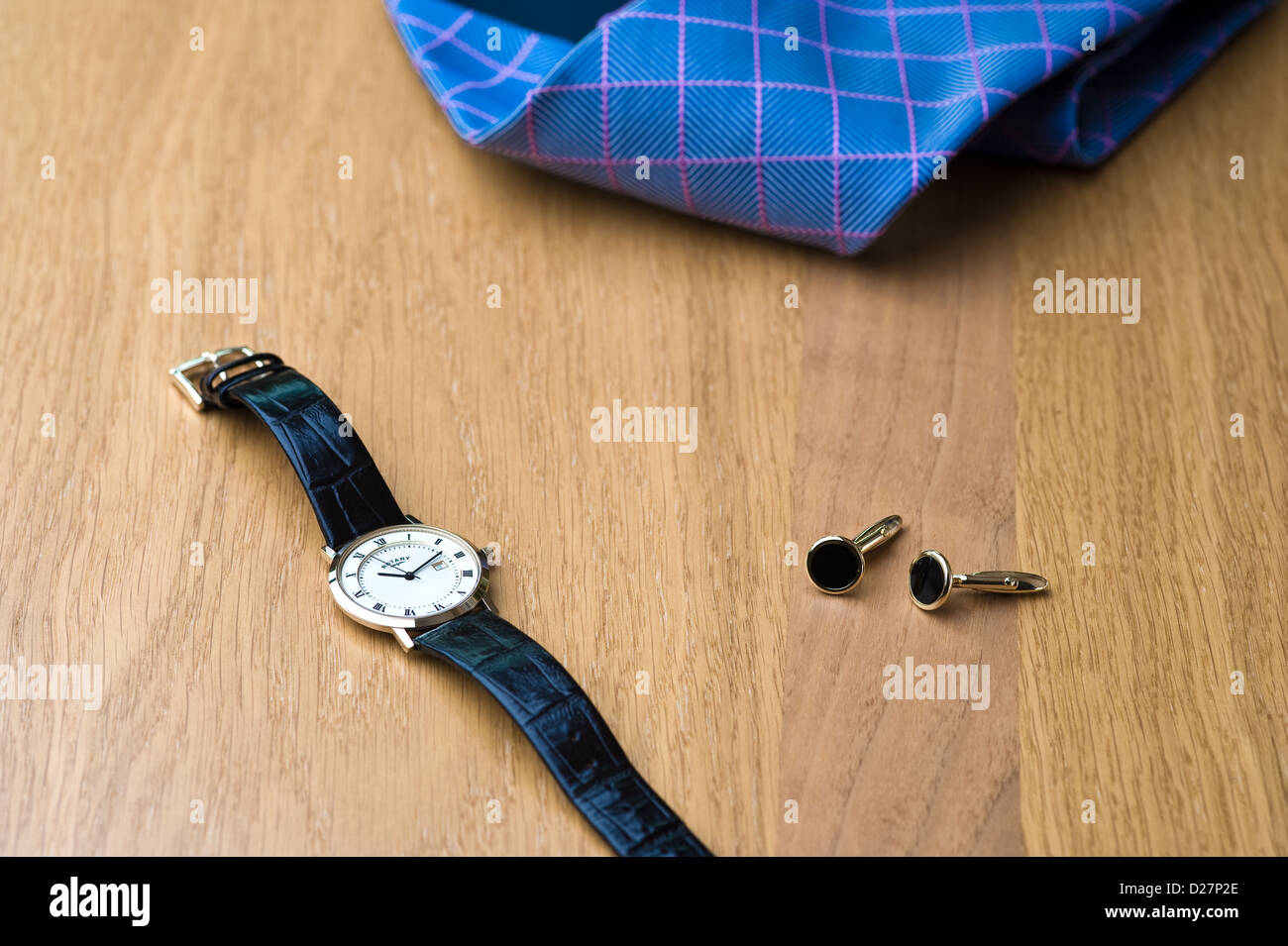 Montre-bracelet, Cravate et Boutons de manchette disposés sur une table en chêne. Banque D'Images