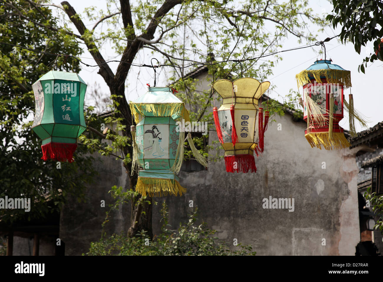 C'est une photo de 4 lampions colorés pendu à une corde près d'un arbre dans un vieux village en Chine. Banque D'Images