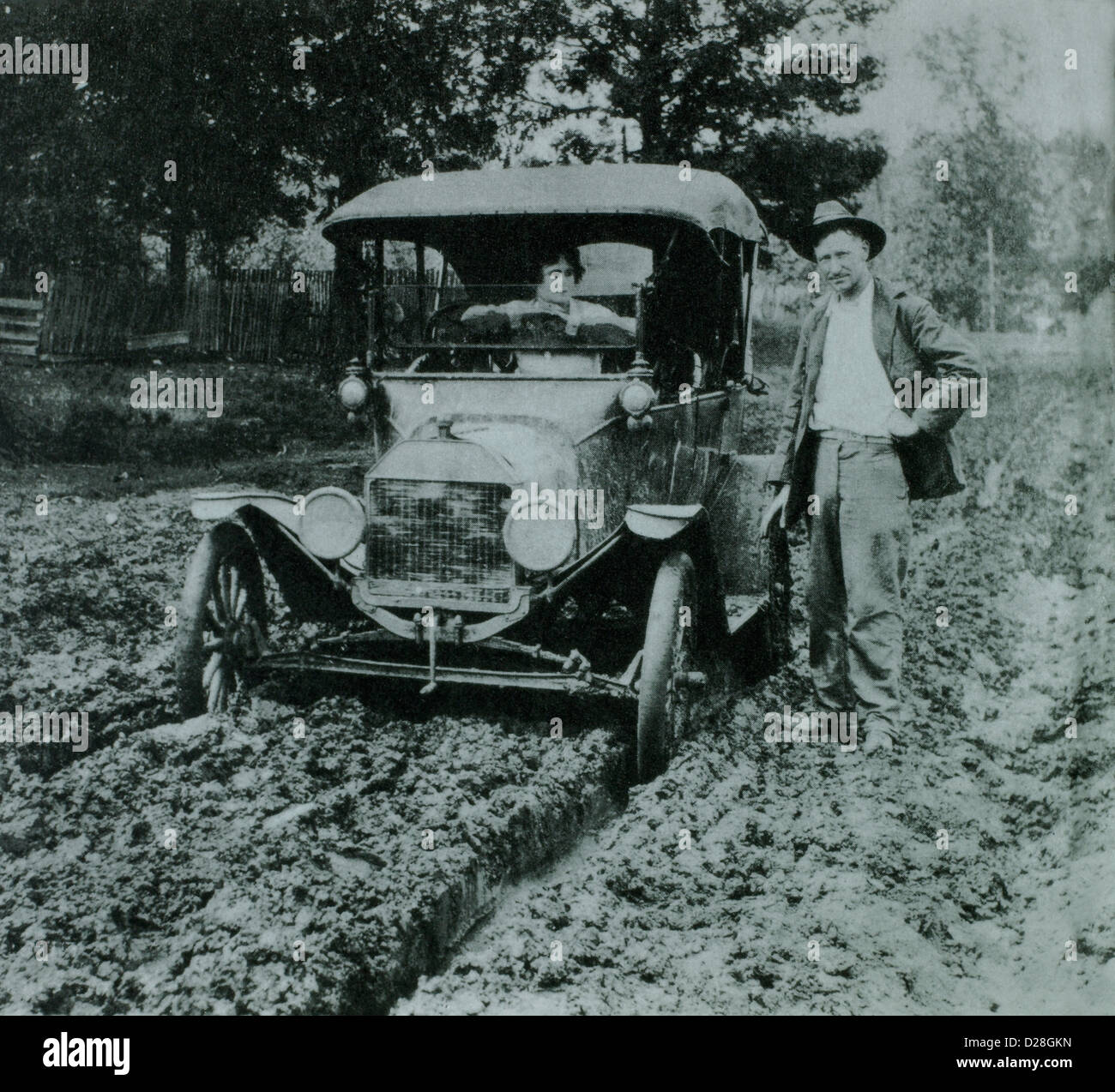 Homme debout à côté de Femme en Ford Modèle T Voiture sur route boueuse, début des années 1900 Banque D'Images