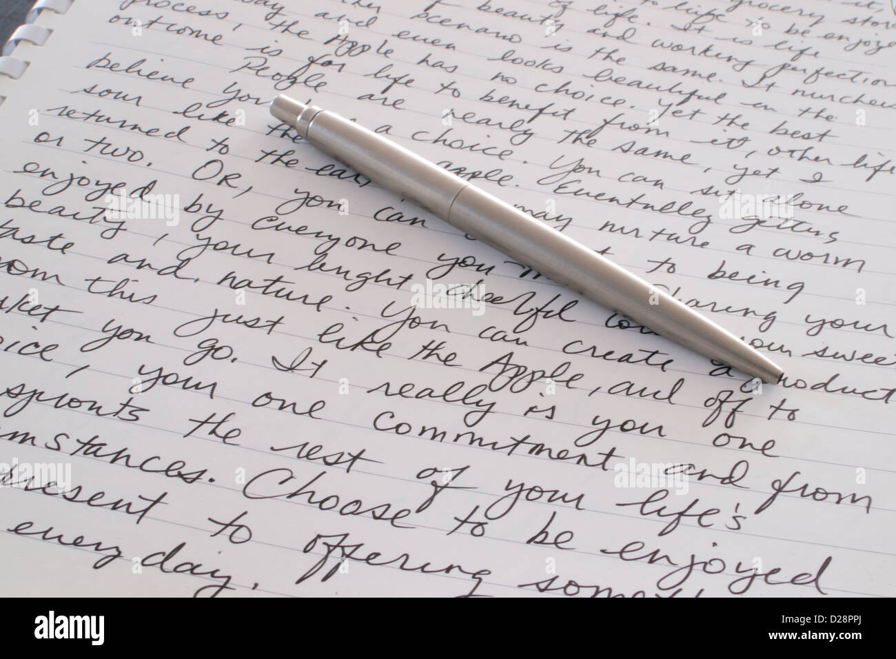 Un stylo à bille en acier inoxydable est posée sur la page écrite d'un bloc-notes à spirale Banque D'Images