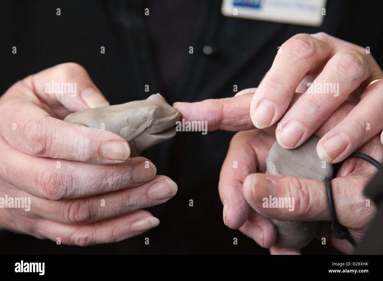 Les déficients visuels avec les soignants sur sortie à Denby Pottery. Toucher l'argile grenouille. Banque D'Images