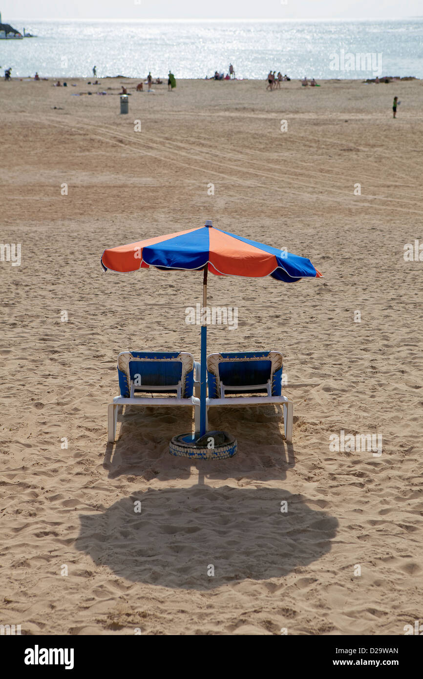 Une image de bleu et orange parasol parasol et 2 transats transats sur la plage de Fuerteventura, Îles Canaries, Espagne. Banque D'Images