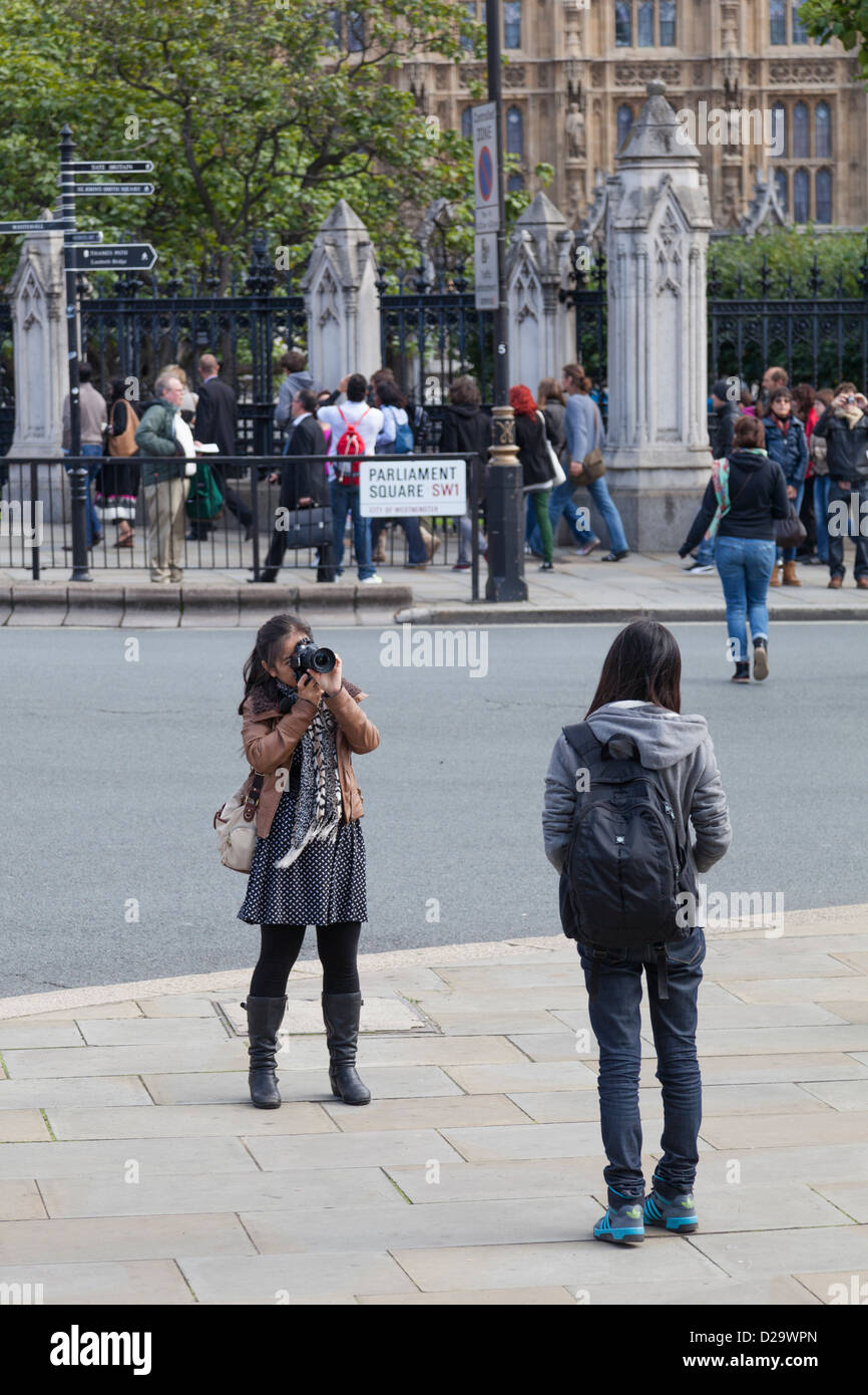 Une fille'prend une photo d'un ami dans la place du Parlement, Londres. Banque D'Images