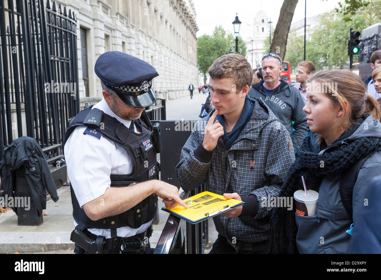 Policier à l'extérieur des portes de Downing Street aide un passant touriste. Banque D'Images