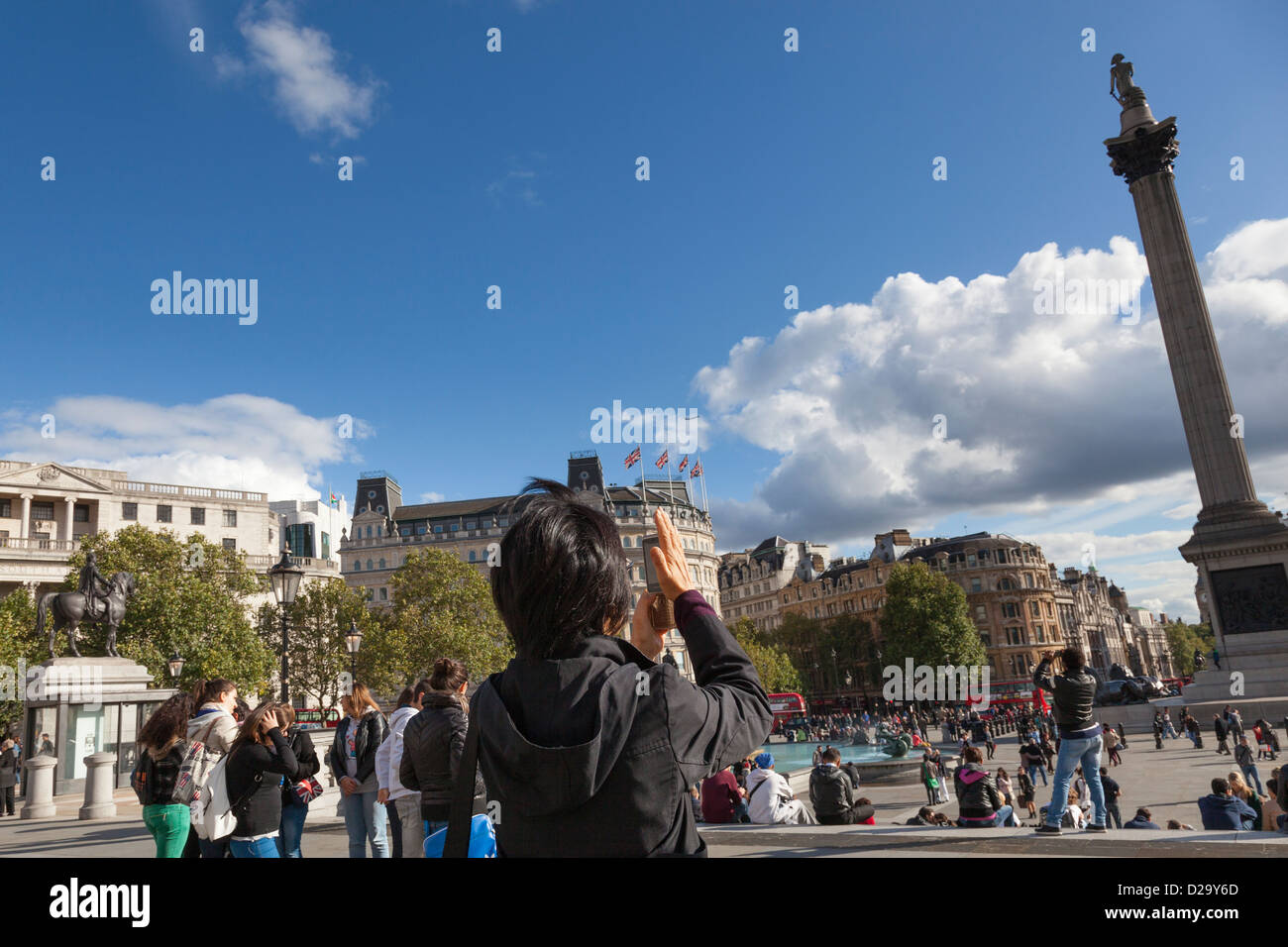 Touriste shields son appareil photo du soleil qu'elle photographie des la Colonne Nelson, Trafalgar Square, Londres. Banque D'Images