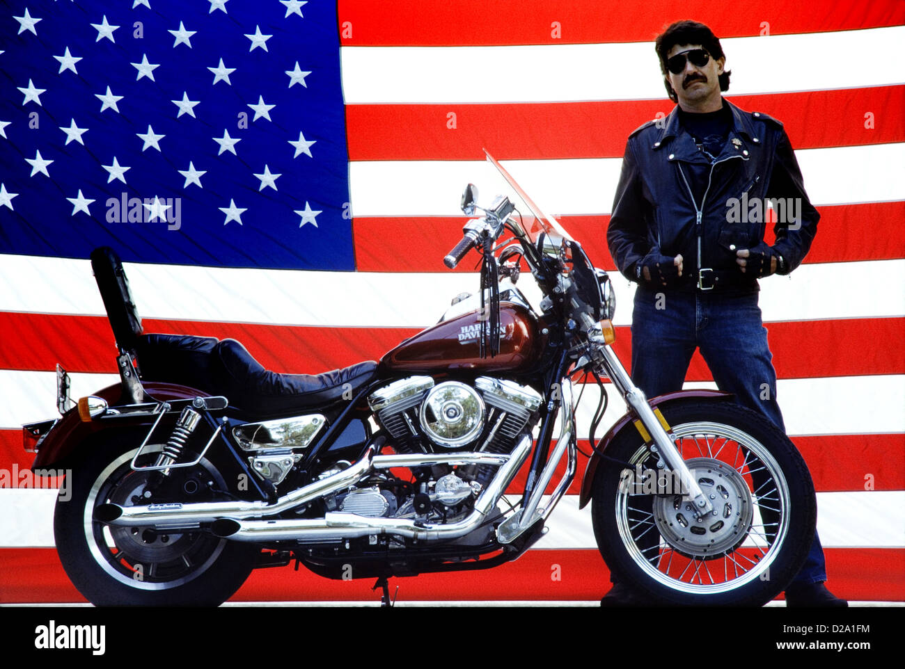 Homme pilote moto avec moto Harley Davidson et drapeau Américain Banque D'Images