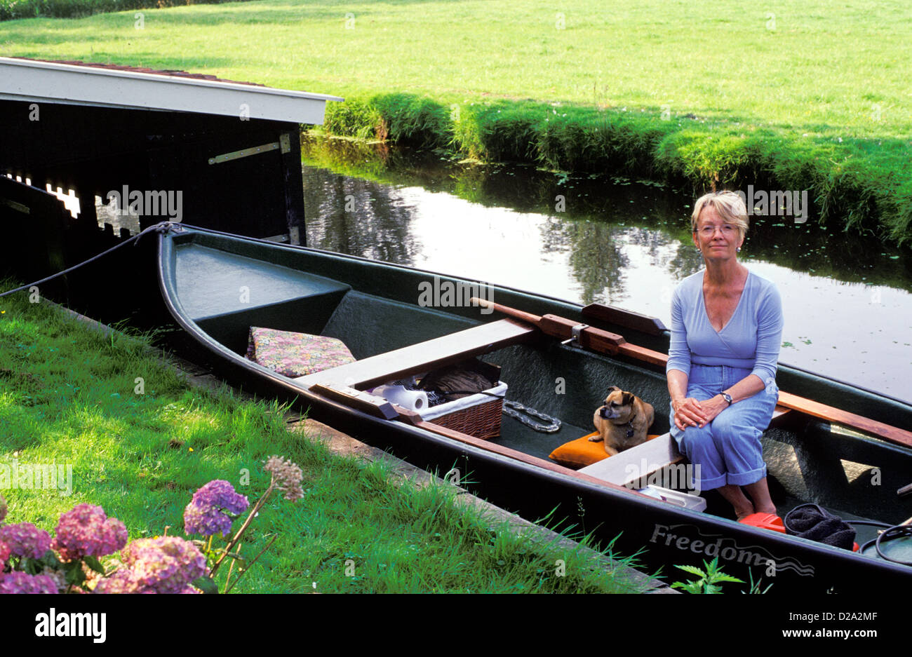 Aux Pays-Bas. Amsterdam. Watergang. Femme et chien sur petit bateau. Canal. Banque D'Images