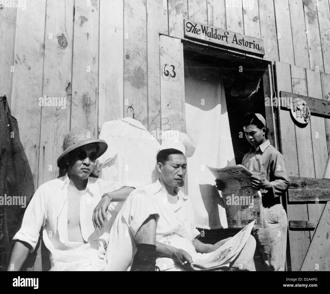 La photographie montre trois hommes assis japonais internés mots construction en bois 'Le Waldorf Astoria' écrit plus de Porte 1942 Banque D'Images