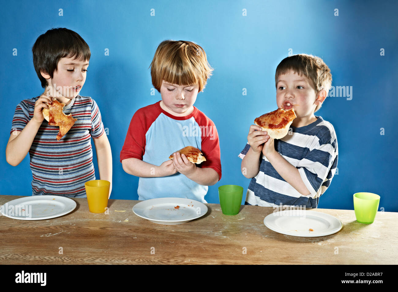 Les garçons de manger une pizza à la table Banque D'Images