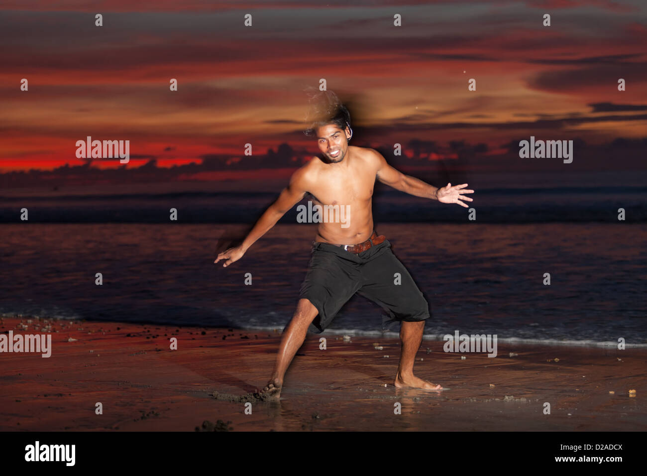 Jeune homme faisant la capoeira sur la plage au coucher du soleil Banque D'Images