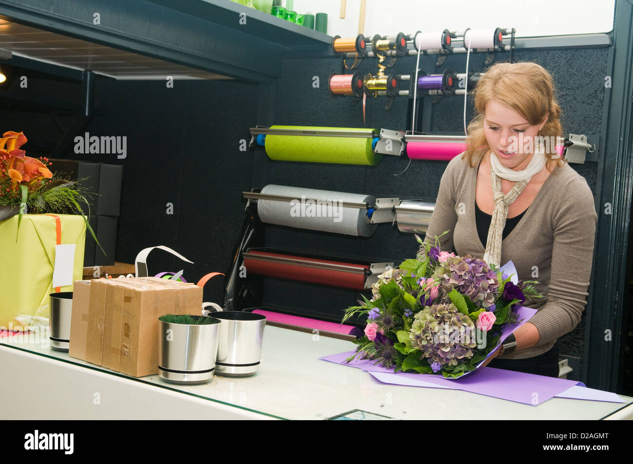 Fleuriste femme travaillant dans une boutique de fleurs, ce qui rend le bouquet pour le client Banque D'Images