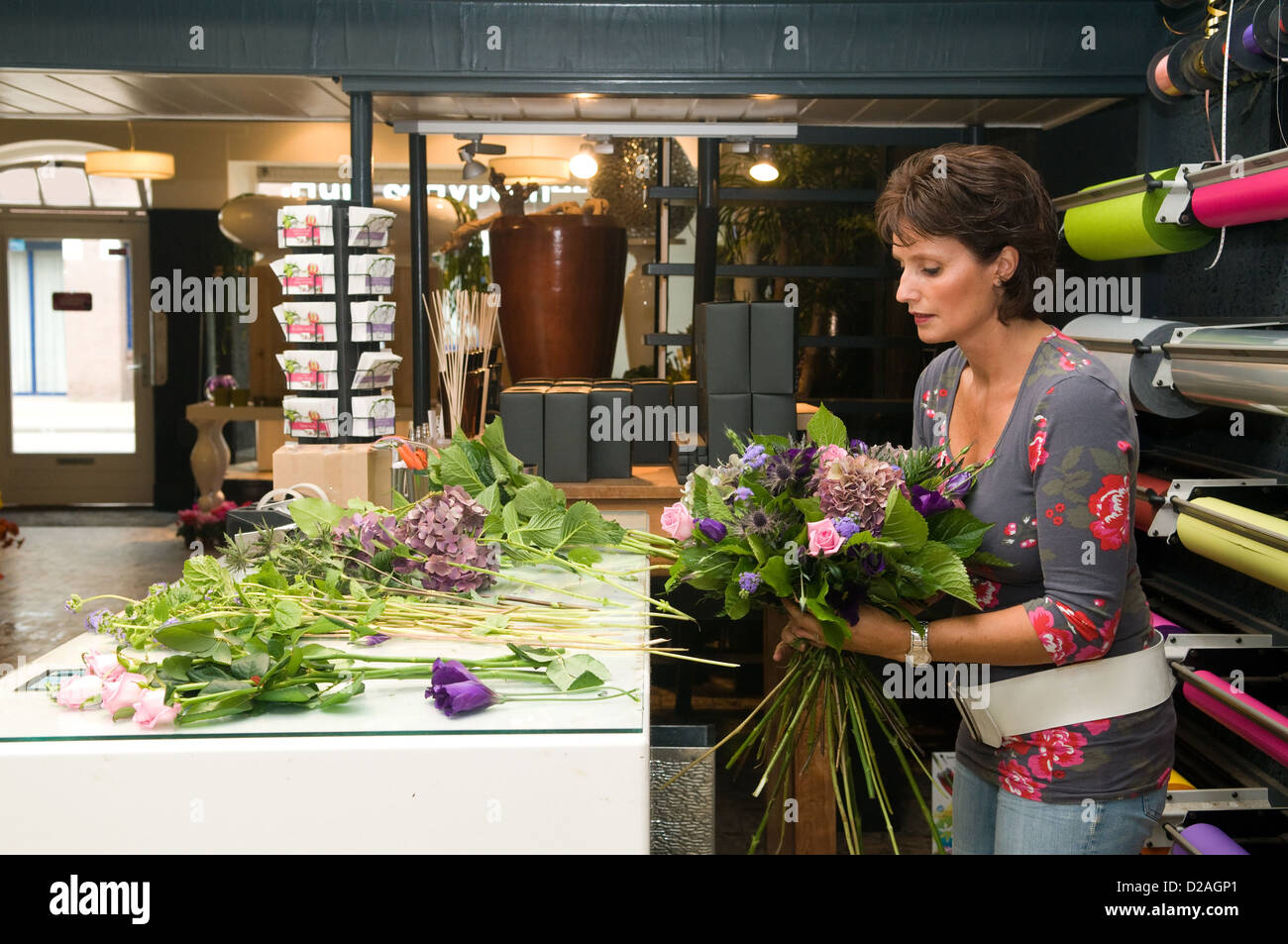 Fleuriste femme travaillant dans une boutique de fleurs, ce qui rend le bouquet pour le client Banque D'Images