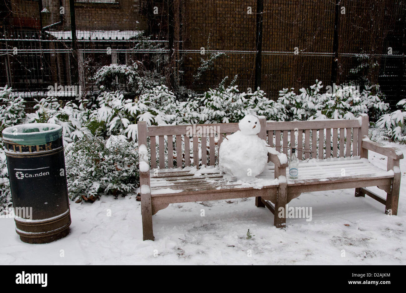 Londres, Royaume-Uni. 18/01/13. Un bonhomme avec une bouteille de vin est assis sur un banc dans un parc près de Tottenham Court Road, que la neige tombe dans le centre de Londres. Banque D'Images