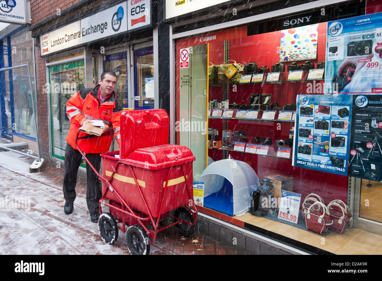 Un facteur de la Royal Mail continue ses livraisons dans le poids de la neige et la glace.Reading, Berkshire, Angleterre, Royaume-Uni. Banque D'Images