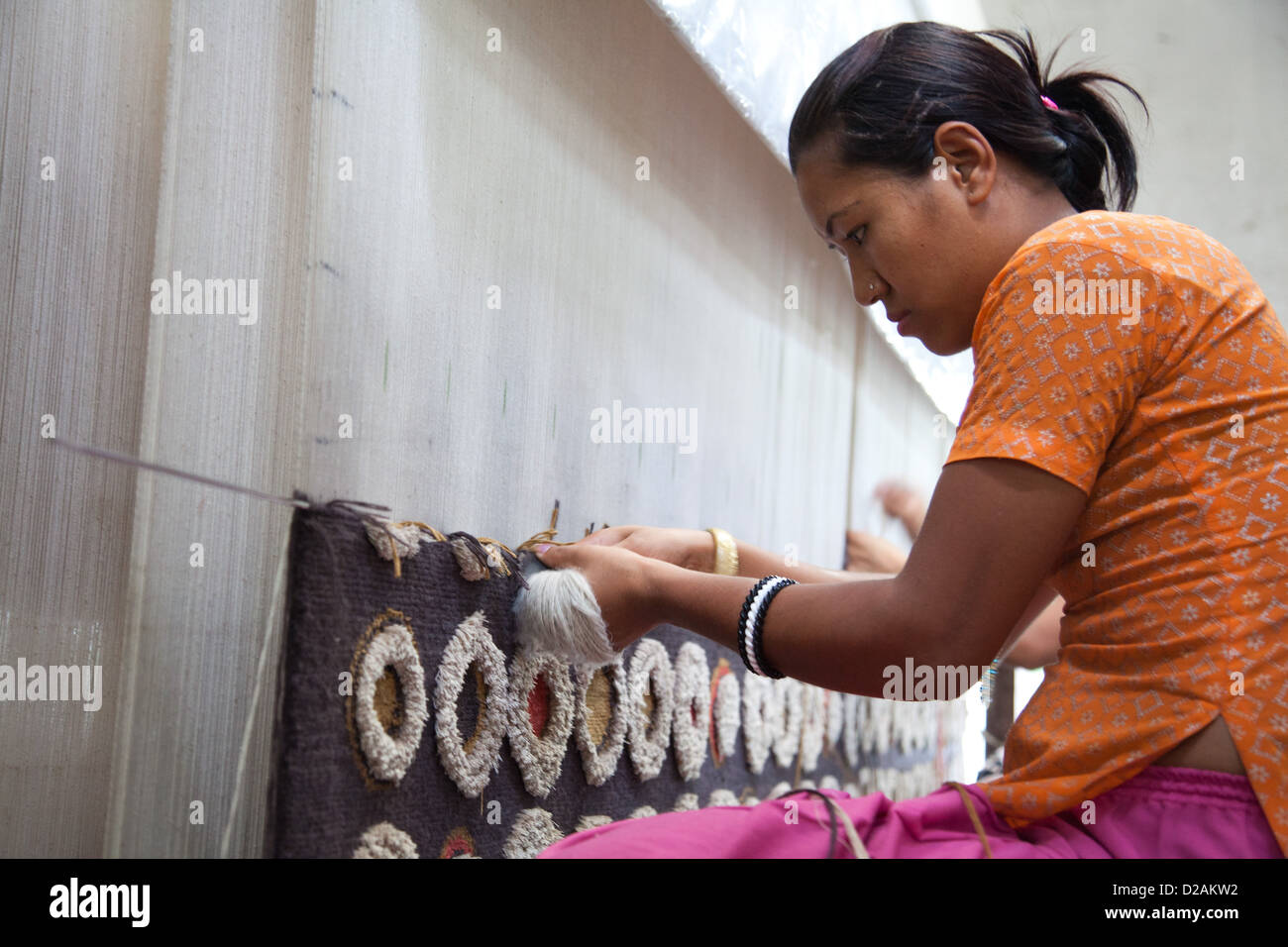 Un travailleur au métier à tisser. Les tapis sont faits de l'ancienne manière avec les travailleurs à l'aide de métiers à tisser énorme et le tissage à la main. Banque D'Images Un travailleur au métier à tisser. Les tapis sont faits de l'ancienne manière avec les travailleurs à l'aide de métiers à tisser énorme et le tissage à la main. Banque D'Images