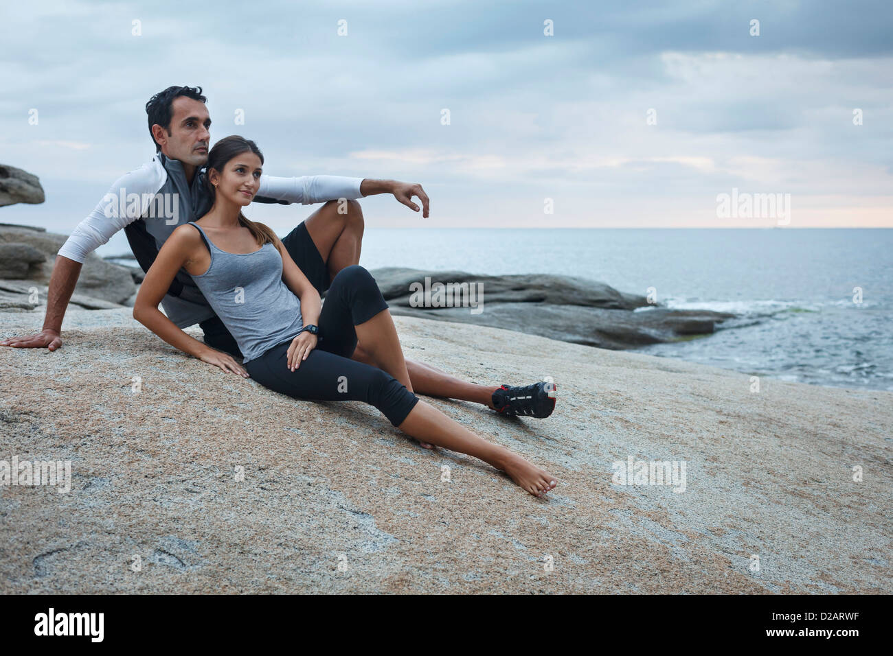 Couple relaxing on boulder par ocean Banque D'Images